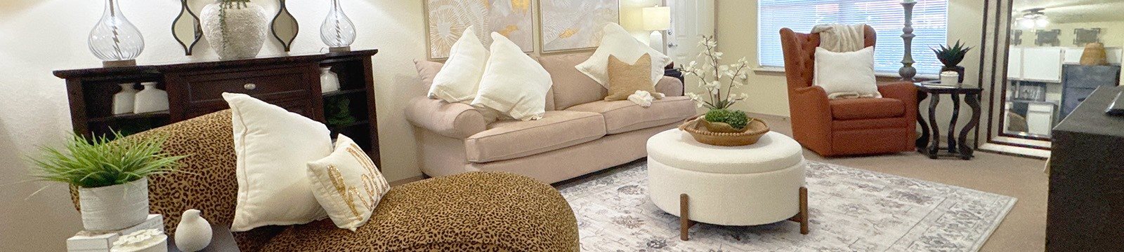 A living room with a leopard print chair and a white ottoman.